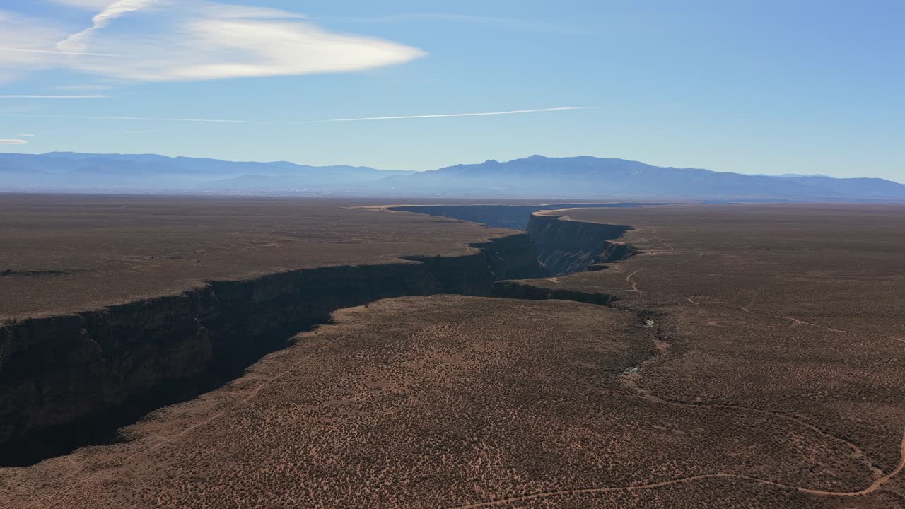 High-angle view of the narrow, winding channel of the Rio Grande River. The water is contained by the towering, vertical cliff walls of the chasm in the arid American Southwest