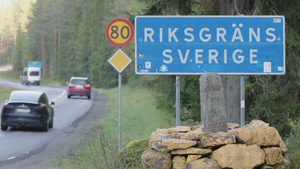 National border sign on roadside between Sweden and Norway with cars passing