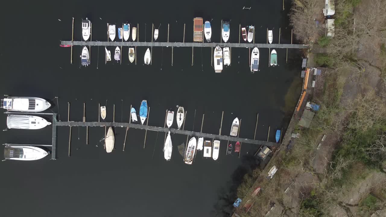 Aerial view of a small boat dock with a few vessels anchored, capturing calm waters and minimal waterfront scenery.