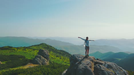 tourist woman stands on a rock with arms raised, at an altitude of 1700m. beautiful landscape of the ukrainian carpathians. sunrise in the mountains, morning in the mountains