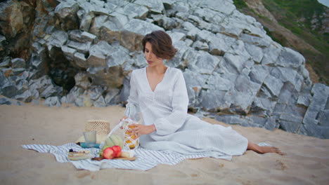 relaxed girl pouring juice on beach picnic. romantic woman enjoying weekend