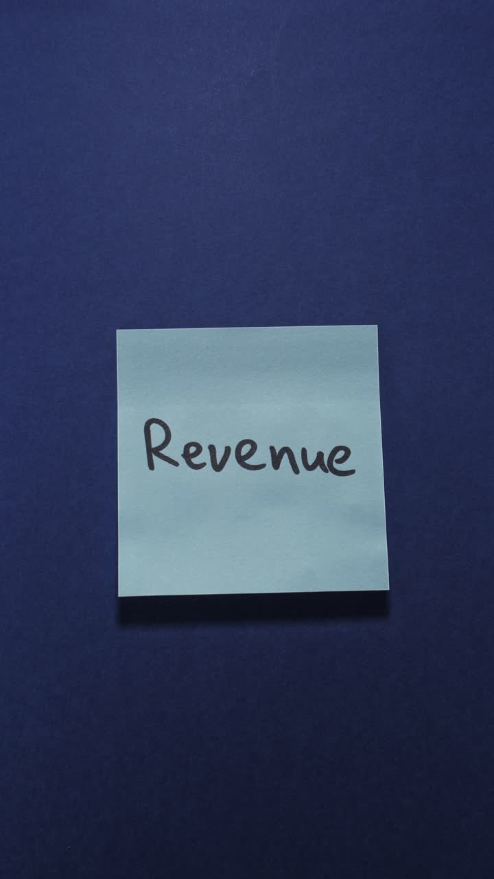 Hands posting Revenue sticky note on dark blue wall, exploring turnover