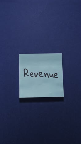 hands posting revenue sticky note on dark blue wall, exploring turnover