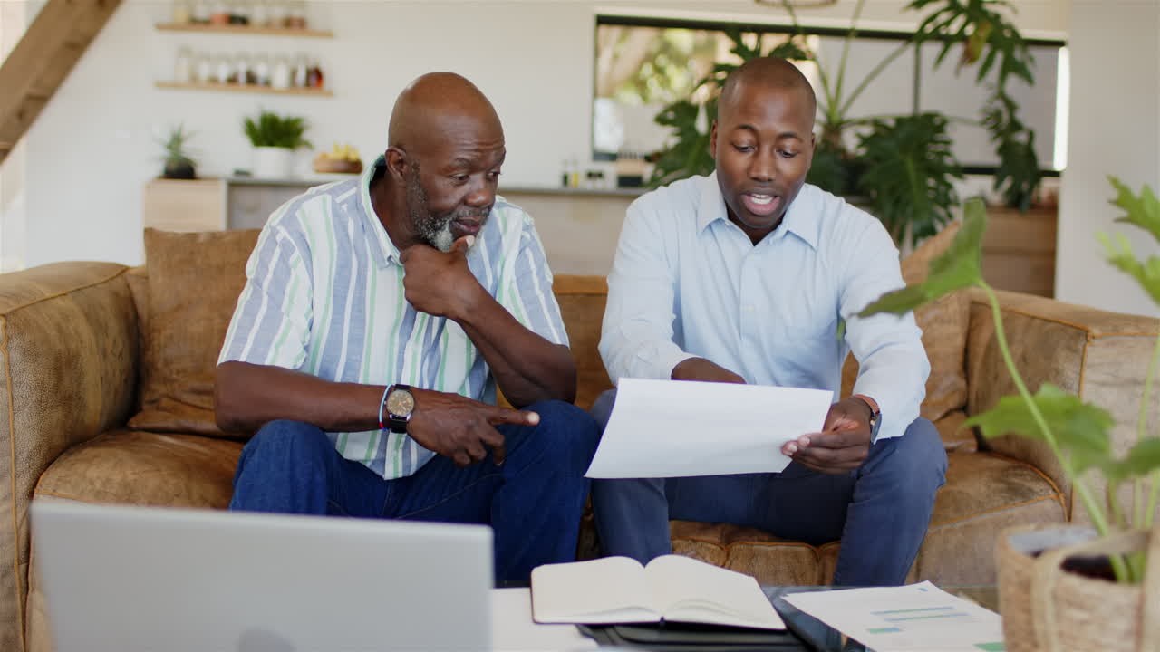 Reviewing documents, financial advisor and client discussing work with laptop and notebook on table
