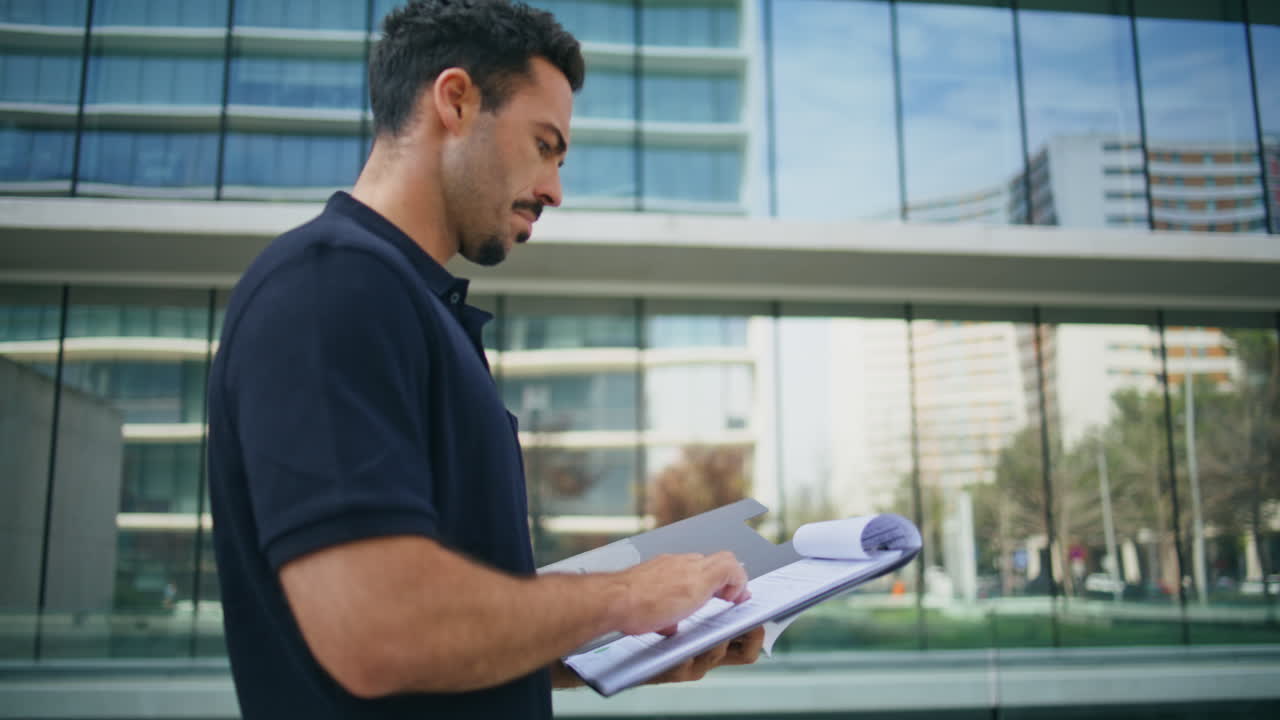 Confident businessman studying documents at street close up. Man holding papers