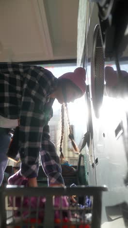 mujer lavando la ropa en una lavandería de autoservicio