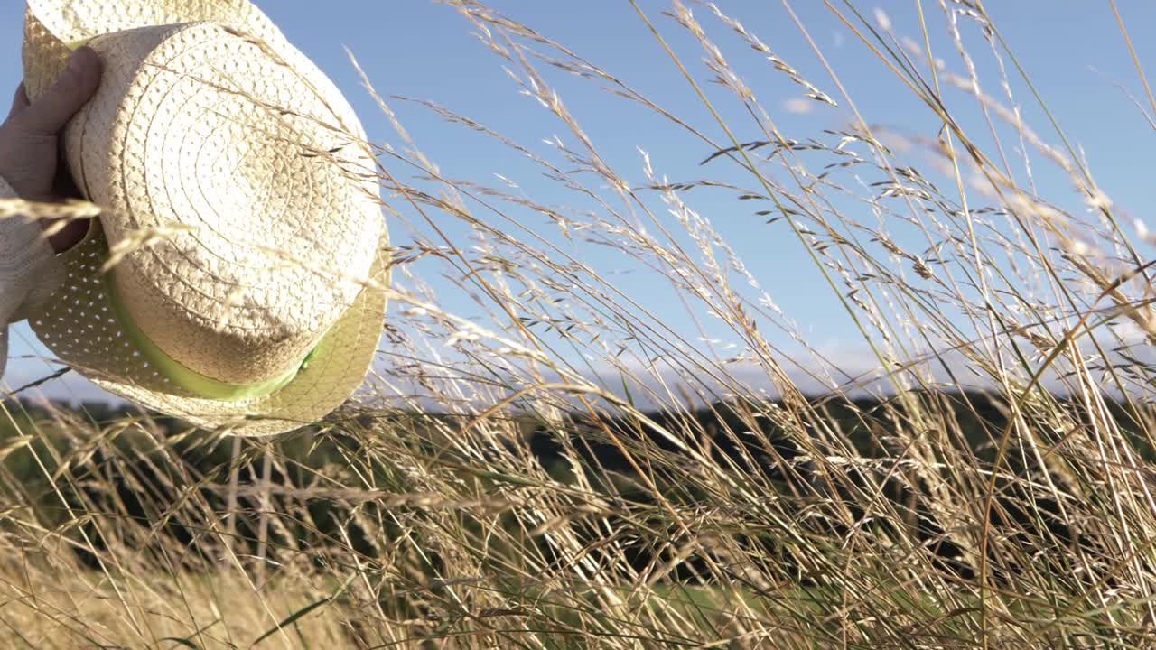 키 큰 잔디 중간 샷에 손을 흔들며 밀짚 모자