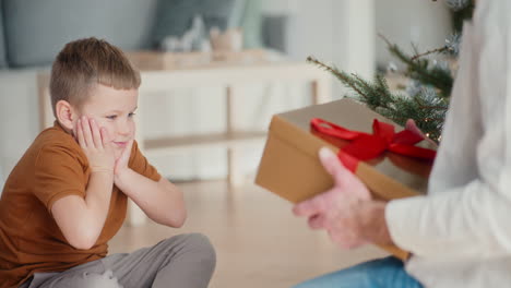 little boy happily opens christmas present