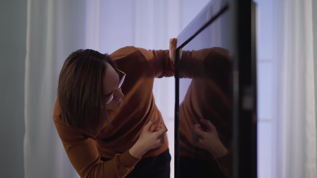 긴 머리카락의 남자가 집에서 스마트 tv 화면에 손가락을  ⁇ 습니다.