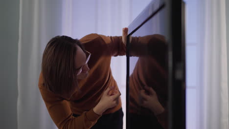 long haired man taps finger on smart tv screen at home