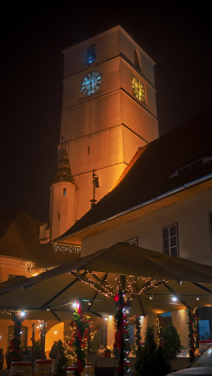 The Council Tower illuminated in the evening between the two main squares of the Historic center in Sibiu, Romania. Vertical