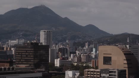 Japanese-Cityscape,-Kokura,-Kitakyushu,-Japan-With-Built-Up-Architecture,-Mountains-and-Neon-Screen