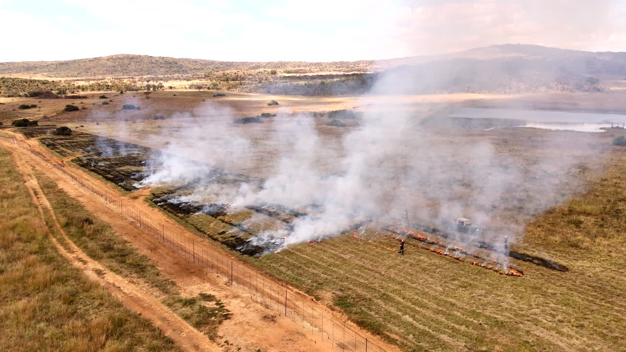 Drone view of planned burn by laborers to clear vegetation from farm field