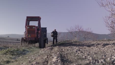 old man collecting rocks in tractor cart in countryside