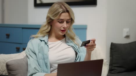 blonde woman sitting at home shopping on internet store using laptop