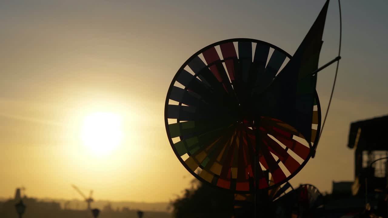 красочное колесо, вращающееся на ветру при заходе солнца в 4к медленном движении 60 кадров в секунду