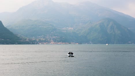 boat on waters of lake como with gorgeous alps mountains of italy