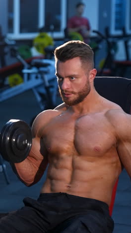 young bodybuilder holding dumbbell. muscular man training with dumbbell in the gym. vertical video