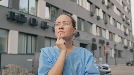 attractive young brunette thinking about her job near hospital building