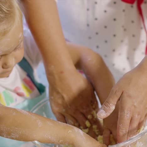 Little girl helping to knead the pastry dough