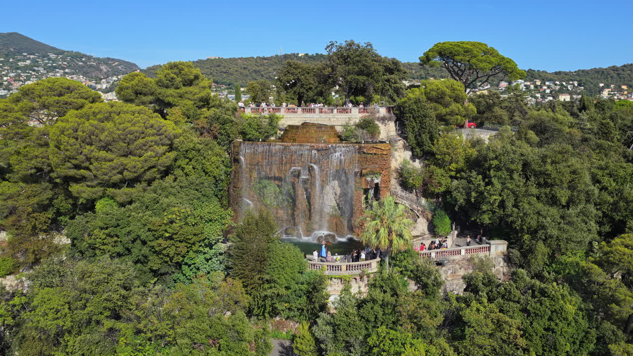 Aerial drone view of the famous waterfall at Castle Hill in Nice, surrounded by lush trees and scenic viewpoints