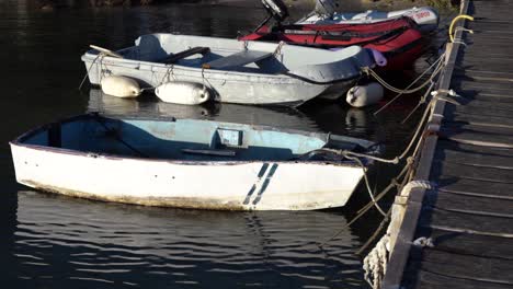 pequeños botes viejos atados al muelle con cuerdas moviéndose lentamente en el agua