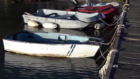 small old boats attached to dock with ropes slowly moving on the water