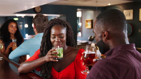 young couple on date meeting for drinks in cocktail bar and making a toast