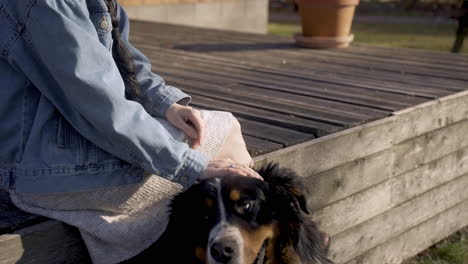 Caucasian-woman-petting-her-dog-outside-a-country-house