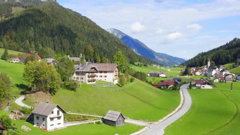 Eine-Aufsteigende-Drohnenaufnahme-Von-Häusern-Oder-Resorts-Im-Tal,-Umgeben-Von-Bergen