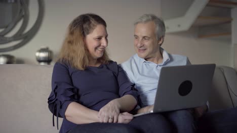 cheerful mid adult couple with laptop excited with new app