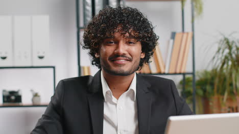 portrait of happy smiling bearded indian business man at home office look away turn head at camera