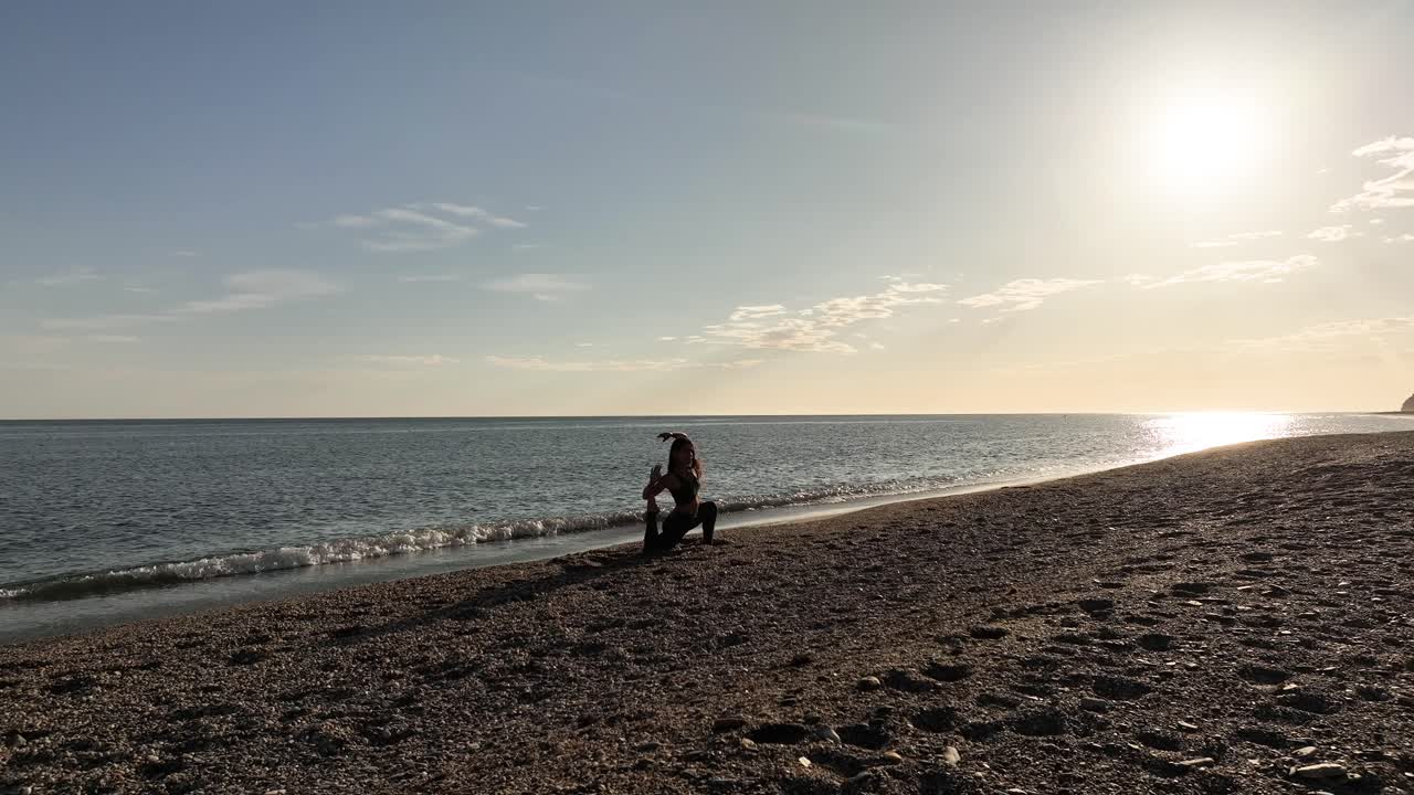 일몰 때 해변에서 요가를 하는 여자