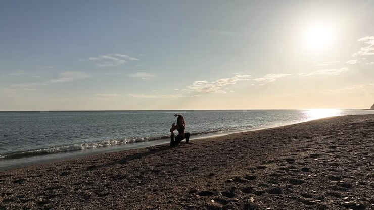 donna che fa yoga sulla spiaggia al tramonto