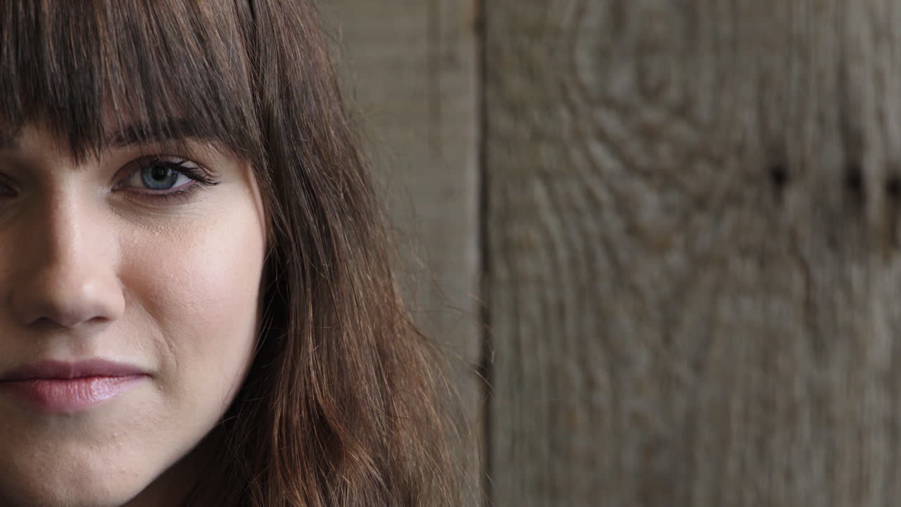 medio rostro retrato de una mujer joven atractiva mirando a la cámara ojos azules calma belleza femenina caucásica en un fondo de madera espacio de copia