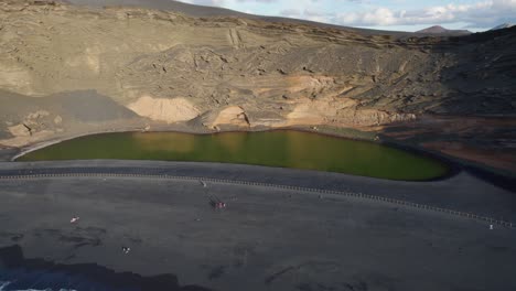 vuelo de drones hacia atrás sobre una playa de arena negra hacia el océano atlántico en la isla volcánica de lanzarote