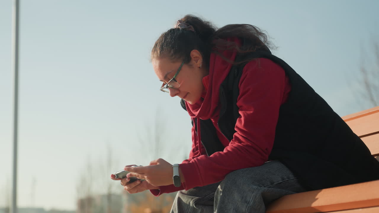 Donna che esamina attentamente i messaggi all'esterno. Donna che legge e rivede tranquillamente i messaggi in un ambiente all'aperto. La signora si dedica con calma ai messaggi godendosi l'ambiente circostante.