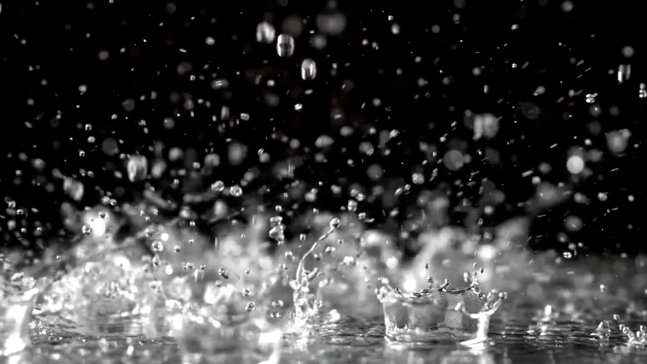 黒い背景を背に、濡れた表面に落ちてはねる雨粒