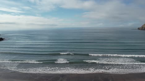 Aerial-approach-to-beautiful-beach-and-turquoise-ocean-waves---Taylors-Mistake-Beach,-New-Zealand