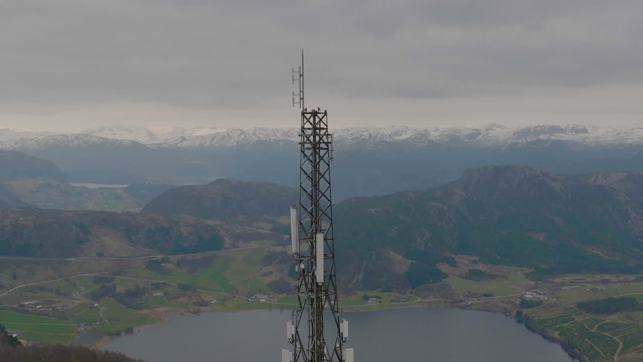 primer plano de un dron orbitando un mástil de teléfono 5g con fondo de montaña, escandinavia