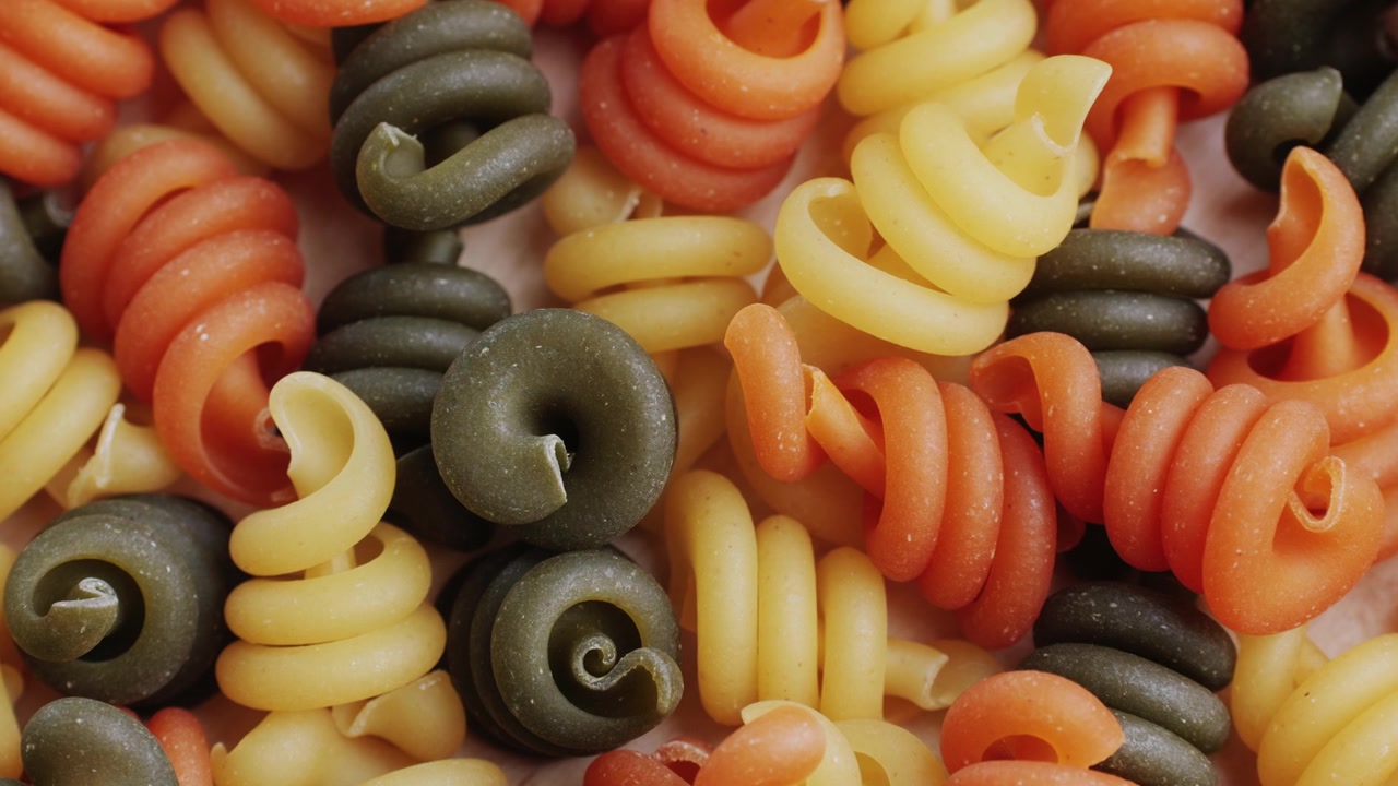 Primo piano di pasta a spirale colorata cruda (Fusilli)