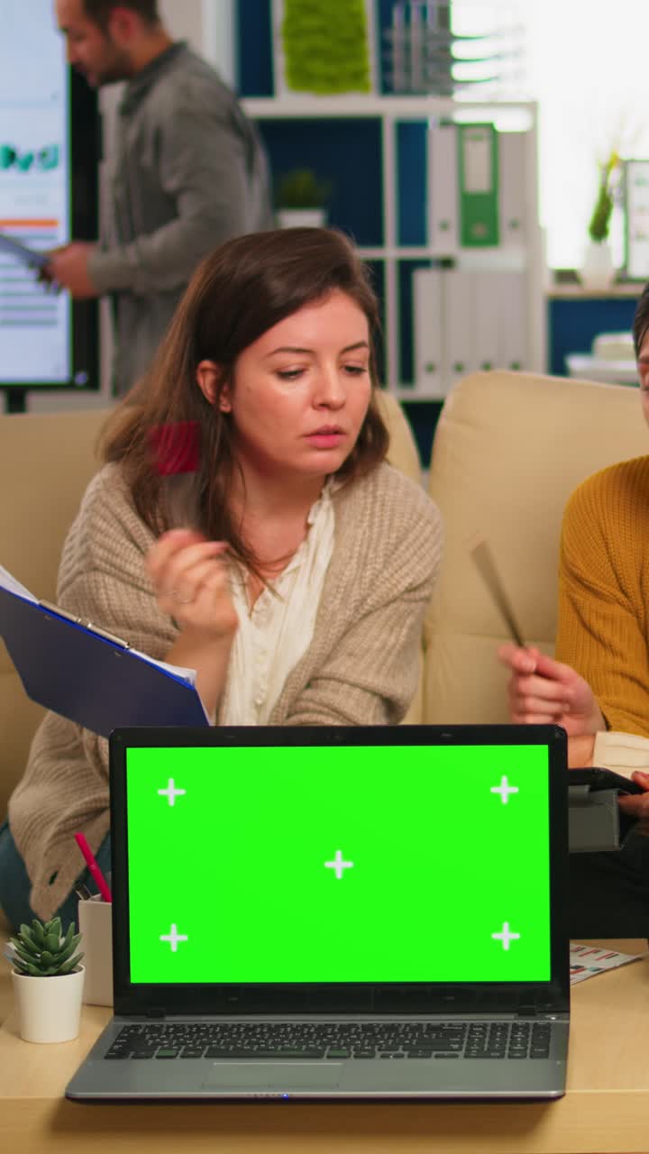 Vertical video Businesswomen discussing in back of laptop with greenscreen