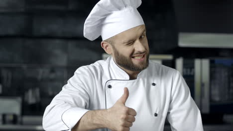 Chef-Hombre-Posando-En-La-Cocina-Profesional.-Chef-Profesional-Con-Los-Pulgares-Hacia-Arriba