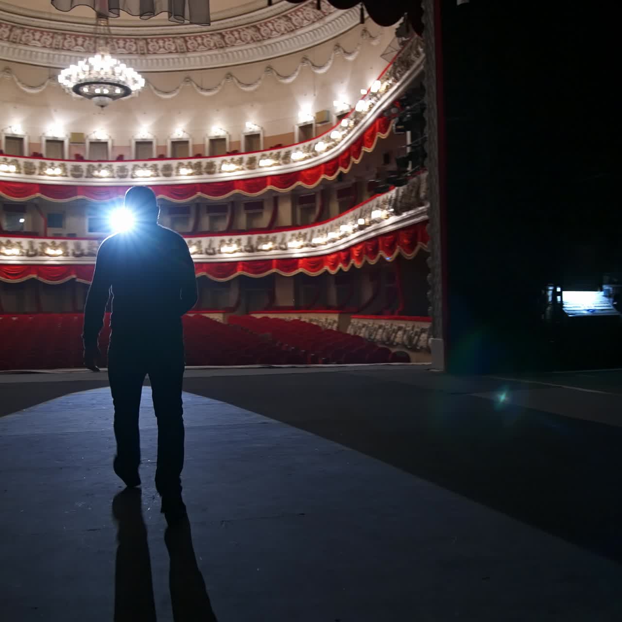 Theater actor has rehearsal before performance. Dark light behind scene. Man in formal clothes with handfree microphone. Classic theater concept