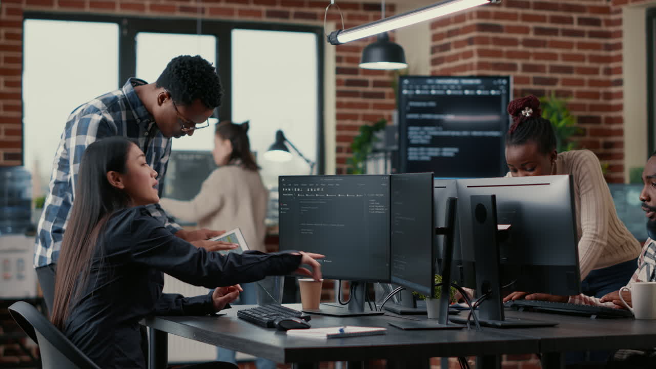 Mixed team of software developers analyzing source code pointing at screens comparing algorithm
