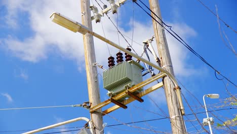 an old power pole converter against a bright blue, cloudy sky