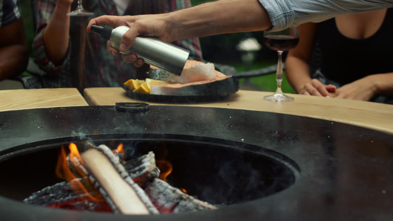셰프의 손이 밖에서 기름을 뿌리고 있습니다.