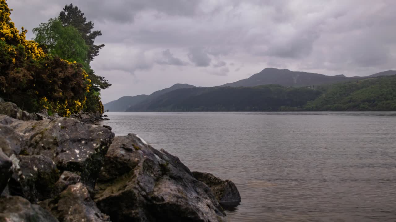 timelapse cinematográfico del lago de las tierras altas escocesas con nubes y montañas brumosas en el fondo