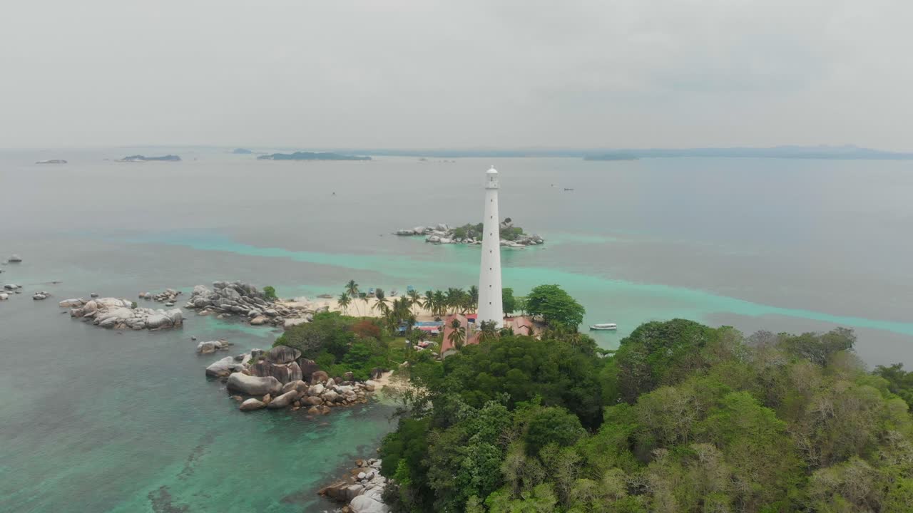 インドネシアのブリトゥン島にあるプルアウ・ランクアス灯台と、その近くのビーチに浮かぶ船の空撮。