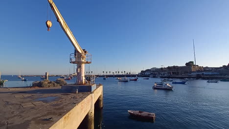 Muelle-De-Pesca-Con-Grúa-De-Hierro,-Equipo-Utilizado-Para-Levantar-Y-Mover-Cargas-Y-Materiales-Pesados,-Barcos-En-El-Agua